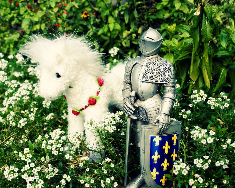 knight figurine in garden with white stuffed horse