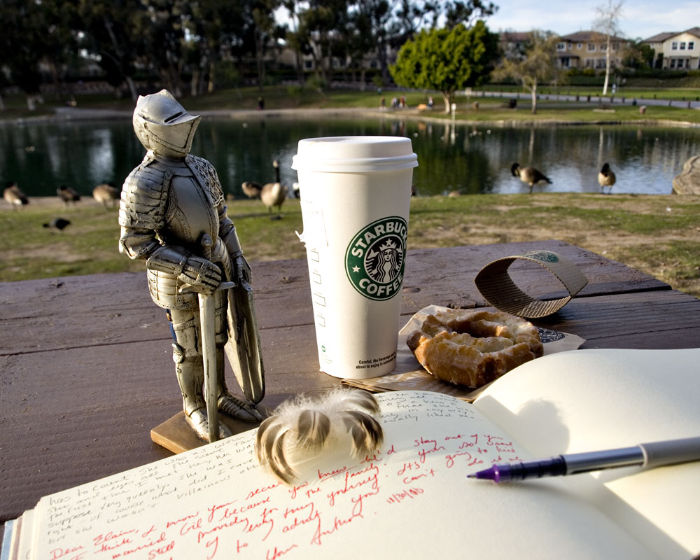 knight figure on picnic bench in park with starbucks cup and notebook