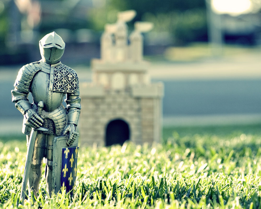 knight figure on lawn with small castle in background