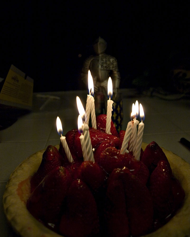 knight figure standing behind strawberry pie with candles