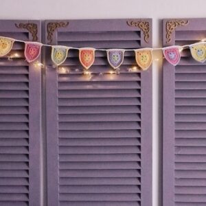 purple wooden screen with crocheted starburst pennant garland and string lights